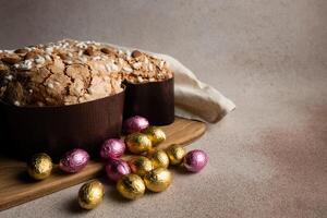 Easter dove cake with chocolate Easter eggs, wooden cutting board on concrete background photo