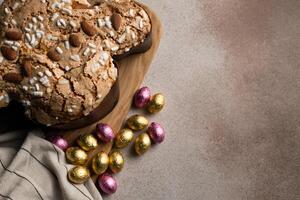 Easter dove cake, chocolate Easter eggs, wooden cutting board on concrete background photo