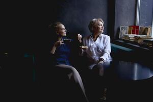 old mother and middle-aged daughter drinking coffee and talking in the cafe photo