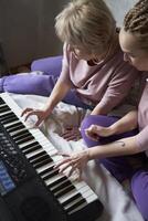 un 60 años madre y un 40 años hija jugar el teclado juntos en el cama a hogar foto