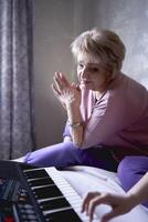 A 60-year-old mother and a 40-year-old daughter play the keyboard together on the bed at home photo