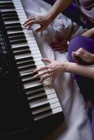 A 60-year-old mother and a 40-year-old daughter play the keyboard together on the bed at home photo