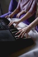 A 60-year-old mother and a 40-year-old daughter play the keyboard together on the bed at home photo