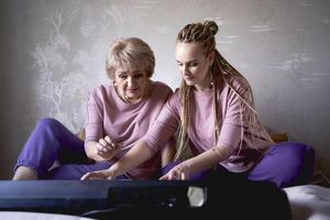 A 60-year-old mother and a 40-year-old daughter play the keyboard together on the bed at home photo