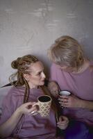 old mother and middle-aged daughter drinking tea and eating marshmallows at home photo