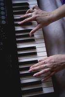 A 60-year-old mother and a 40-year-old daughter play the keyboard together on the bed at home photo