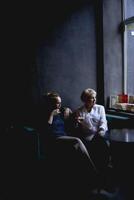 old mother and middle-aged daughter drinking coffee and talking in the cafe photo