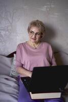 an elderly woman works with laptop at home photo