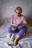 elderly woman reads a book at home photo