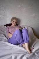 elderly woman reads a book at home photo