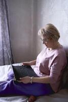 an elderly woman works with laptop at home photo