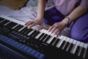 A 60-year-old mother and a 40-year-old daughter play the keyboard together on the bed at home photo