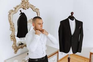 Business shirt. A man in a white shirt fastens the buttons. Young politician, male style, businessman buttoning shirt, male hands close-up, american, european businessman photo