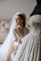 Young bride in beautiful wedding dress putting on shoes indoors. Bride dresses shoes before the wedding ceremony. Detail of bride putting on high heeled sandal wedding shoes. Wedding bride shoes. photo