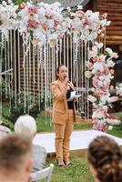 Boda ceremonia en naturaleza. el Maestro de ceremonias a el Boda durante el habla invita el novia y novio a el ceremonia. foto