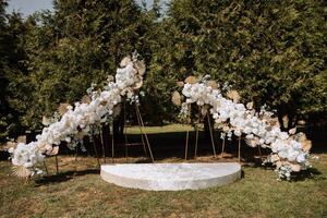 Wedding arch made of white flowers in nature. Summer wedding. Preparation for the wedding ceremony. Everything is ready for the celebration. photo