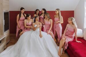 un hermosa novia y su damas de honor son teniendo divertido en el Mañana. Boda celebracion. contento muchachas a su mejor amigos boda. un hermosa y elegante novia con su damas de honor foto