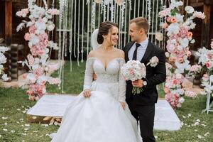 A handsome groom and an elegant bride in a lush white dress are walking in a summer park. Happy bride and groom getting ready for their best day. photo