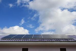 Instalar en pc nuevo solar paneles en el metal sábana techo de el casa dónde electricidad es todavía inaccesible. antecedentes con muchos nubes y azul cielo foto