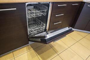 open door of an empty dishwasher in the kitchen photo