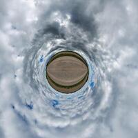 simple green tiny planet without buildings in blue sky with beautiful clouds. Transformation of spherical panorama 360 degrees. Spherical abstract aerial view. Curvature of space. photo