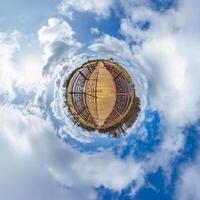 simple green tiny planet without buildings in blue sky with beautiful clouds. Transformation of spherical panorama 360 degrees. Spherical abstract aerial view. Curvature of space. photo