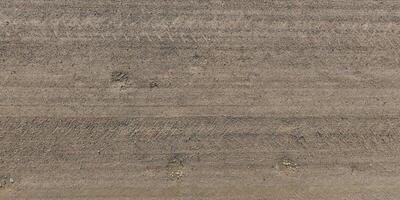 panorama of road from above on surface of gravel road with car tire tracks in countryside photo