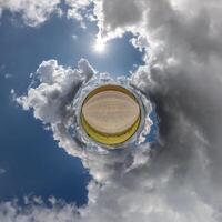 simple green tiny planet without buildings in blue sky with beautiful clouds. Transformation of spherical panorama 360 degrees. Spherical abstract aerial view. Curvature of space. photo