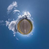 simple green tiny planet without buildings in blue sky with beautiful clouds. Transformation of spherical panorama 360 degrees. Spherical abstract aerial view. Curvature of space. photo