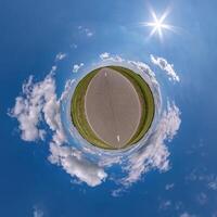 simple green tiny planet without buildings in blue sky with beautiful clouds. Transformation of spherical panorama 360 degrees. Spherical abstract aerial view. Curvature of space. photo