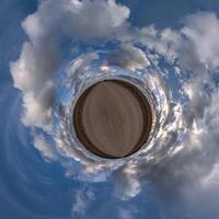 simple green tiny planet without buildings in blue sky with beautiful clouds. Transformation of spherical panorama 360 degrees. Spherical abstract aerial view. Curvature of space. photo