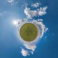 simple green tiny planet without buildings in blue sky with beautiful clouds. Transformation of spherical panorama 360 degrees. Spherical abstract aerial view. Curvature of space. photo