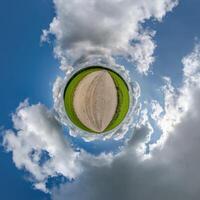 simple green tiny planet without buildings in blue sky with beautiful clouds. Transformation of spherical panorama 360 degrees. Spherical abstract aerial view. Curvature of space. photo