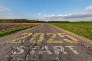 números 2025 Vamos y comienzo en asfalto la carretera con grietas autopista con amanecer o puesta de sol cielo antecedentes. concepto de destino en futuro, libertad, trabajo comenzar, correr, planificación, desafío, objetivo, nuevo año foto