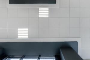 cassette stretched or suspended ceiling with square halogen spots lamps and drywall construction in empty room in house or office with column. Looking up view photo