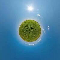 simple green tiny planet without buildings in blue sky with beautiful clouds. Transformation of spherical panorama 360 degrees. Spherical abstract aerial view. Curvature of space. photo