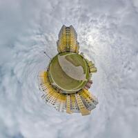 tiny planet in blue sky with clouds in city center near modern skyscrapers. Transformation of spherical 360 panorama in abstract aerial view. photo