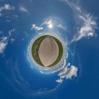 simple green tiny planet without buildings in blue sky with beautiful clouds. Transformation of spherical panorama 360 degrees. Spherical abstract aerial view. Curvature of space. photo