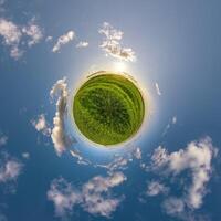 simple green tiny planet without buildings in blue sky with beautiful clouds. Transformation of spherical panorama 360 degrees. Spherical abstract aerial view. Curvature of space. photo