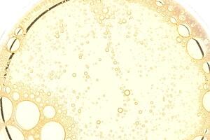 Abstract yellow oil bubbles background. Cosmetic liquid beauty product. photo