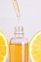 ultra hidratante facial vitamina C suero anuncio, cuentagotas botella terminado rebanado naranja en blanco antecedentes. protección de la piel concepto. foto