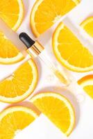 Dropper glass bottle branding mockup. Cosmetic pipette. Trendy white background with sliced oranges. Concept of organic and beauty cosmetics. Harsh sunlight. Top view photo