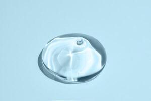 Glycerin gel texture. Transparent serum drop on blue background. Liquid gel moisturizer with bubbles macro photo