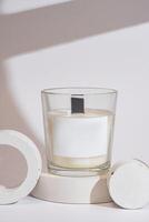 Handmade scented candles in a glass with on a podium. Soy wax candles with a wooden wick. Front view. photo