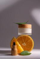 Refreshing orange citrus fruit beauty treatment for skincare. Moisturizer face cream and beauty serum in bamboo dropper bottle on gray background. Natural health care skin tonic concept photo