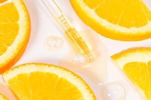 close up of pipette with pouring liquid serum with vitamin C and shadows on white background. Trendy cosmetics shot photo