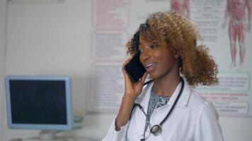 African american nurse talking on the phone in a modern hospital. Concept of medicine, health care and people video