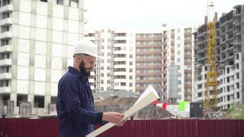 Architect or engineer working in hard hat browsing building project of construction site with blueprint plan video