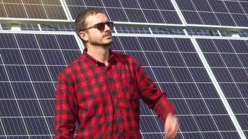 retrato de un exitoso joven ingeniero en el antecedentes de un solar poder estación. ingeniero instalando nuevo soleado baterías video