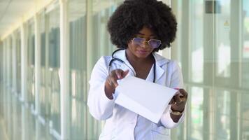 dichtbij omhoog van Afrikaanse Amerikaans dokter in ziekenhuis. vrouw dokter in ziekenhuis nemen notities, detailopname video